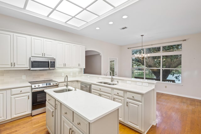 kitchen featuring a kitchen island with sink, decorative backsplash, appliances with stainless steel finishes, and a sink