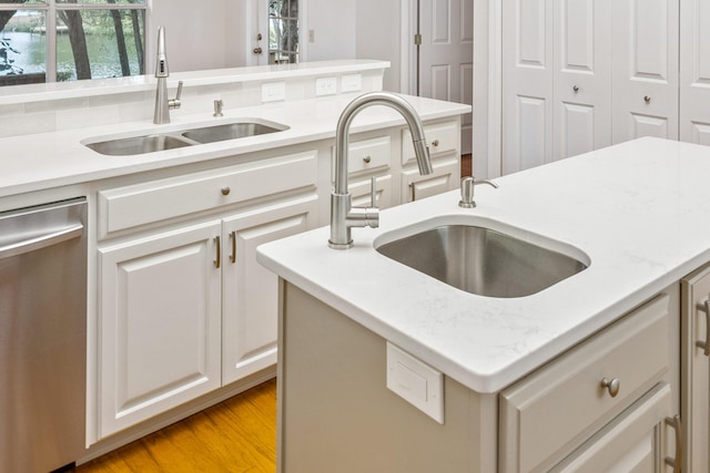 kitchen featuring dishwasher, white cabinetry, light wood-type flooring, and a sink