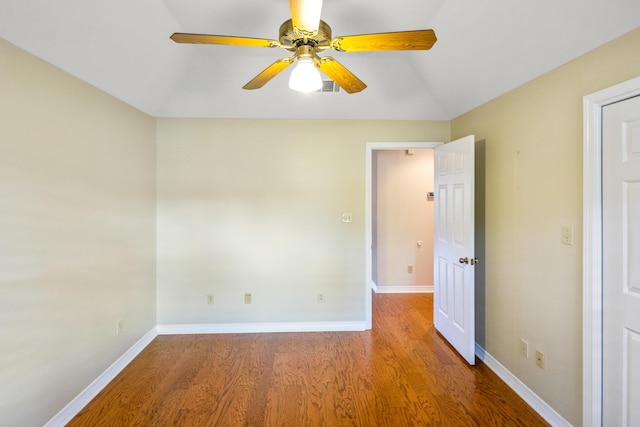 empty room featuring ceiling fan, visible vents, baseboards, and wood finished floors