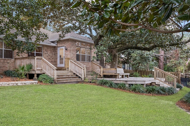 rear view of house with a deck, a lawn, brick siding, and roof with shingles