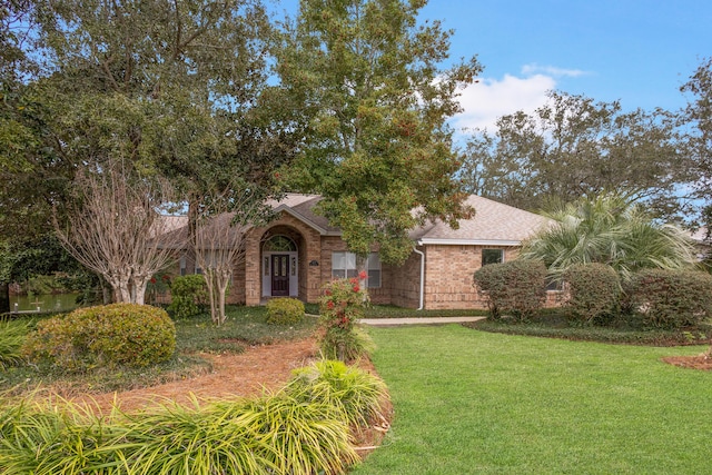 view of front of house with a front lawn, brick siding, and a shingled roof