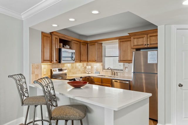 kitchen with tasteful backsplash, brown cabinets, a peninsula, stainless steel appliances, and a sink