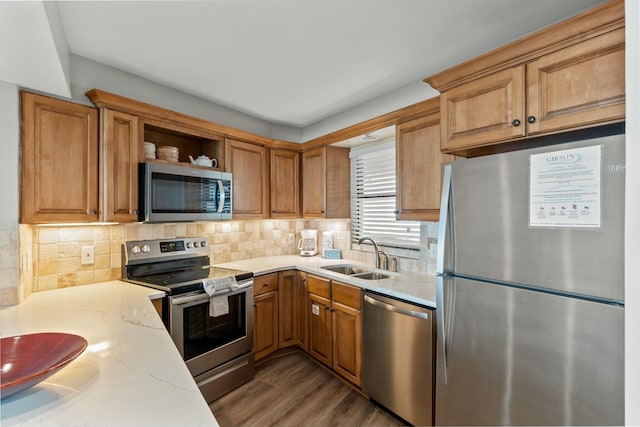 kitchen with tasteful backsplash, light stone counters, stainless steel appliances, and a sink