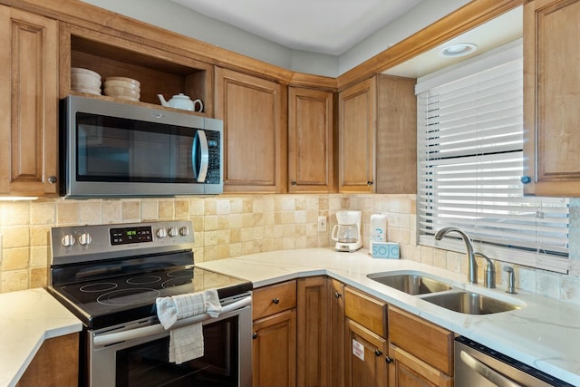 kitchen featuring light stone countertops, backsplash, stainless steel appliances, and a sink