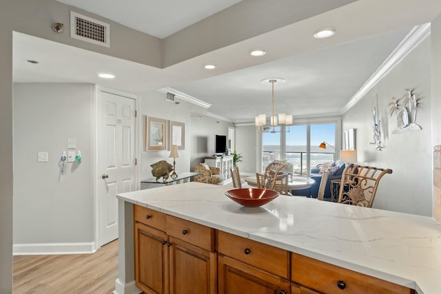 kitchen featuring ornamental molding, brown cabinetry, visible vents, and open floor plan