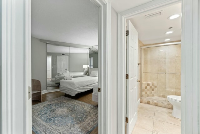 full bathroom with toilet, a shower stall, ensuite bath, tile patterned flooring, and baseboards