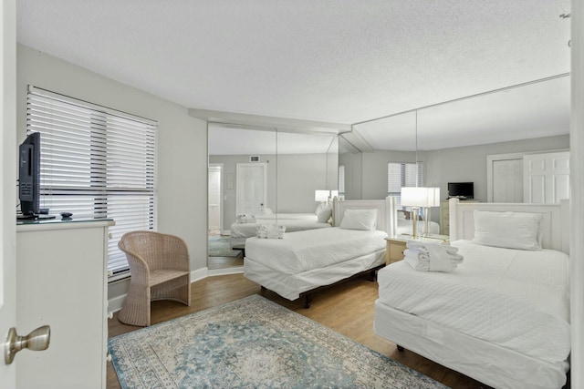 bedroom with a textured ceiling, wood finished floors, and baseboards