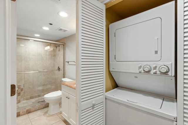 bathroom with tile patterned flooring, toilet, visible vents, stacked washer / drying machine, and a stall shower