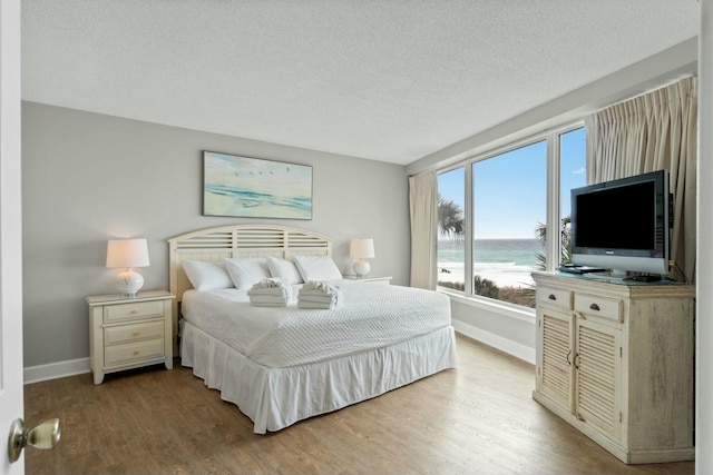 bedroom with a textured ceiling, baseboards, and wood finished floors