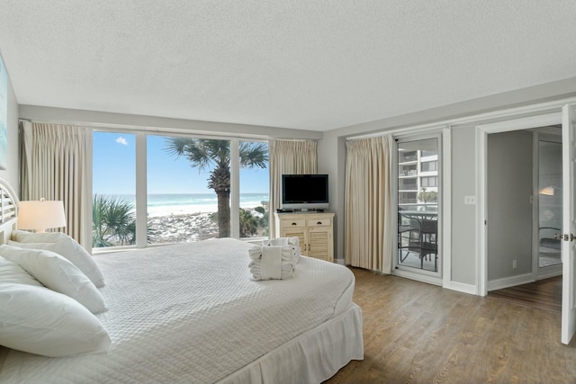 bedroom with access to outside, a textured ceiling, baseboards, and wood finished floors