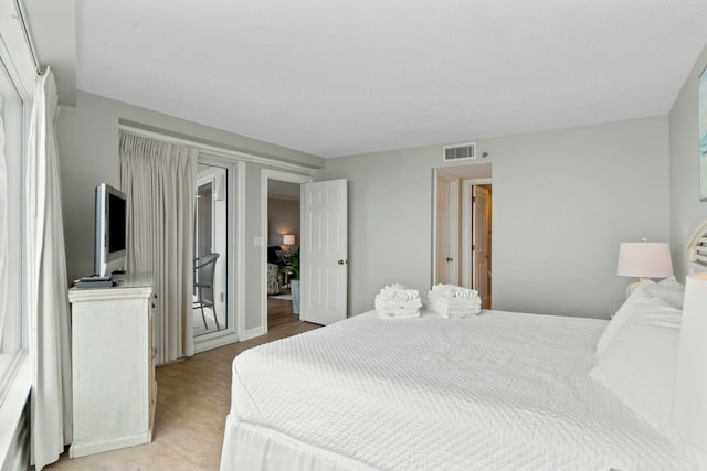 bedroom with access to exterior, light wood-style flooring, and visible vents