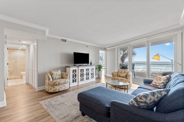 living room with ornamental molding, baseboards, visible vents, and light wood finished floors