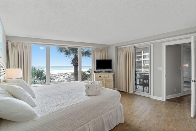 bedroom featuring a textured ceiling, baseboards, wood finished floors, and access to exterior