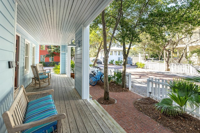 wooden terrace featuring a porch and fence