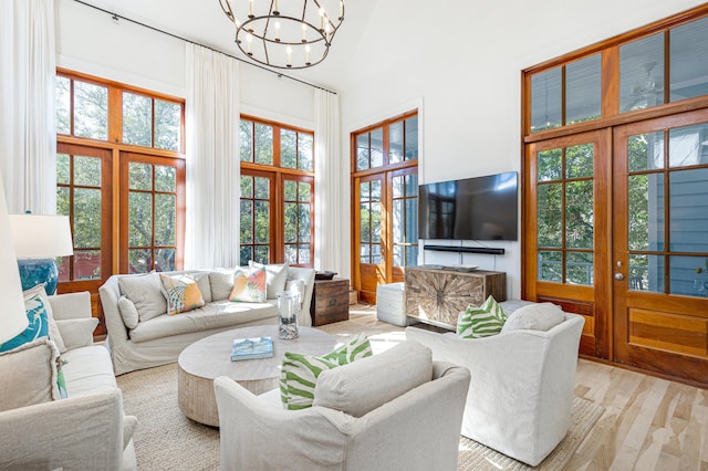 living room with an inviting chandelier, light wood-style flooring, and a high ceiling