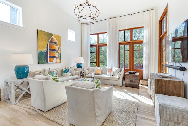 living area with light wood-style floors, a high ceiling, and a chandelier