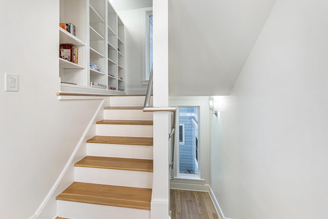 staircase featuring wood finished floors and baseboards