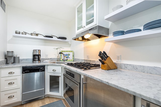 kitchen with glass insert cabinets, appliances with stainless steel finishes, under cabinet range hood, white cabinetry, and open shelves