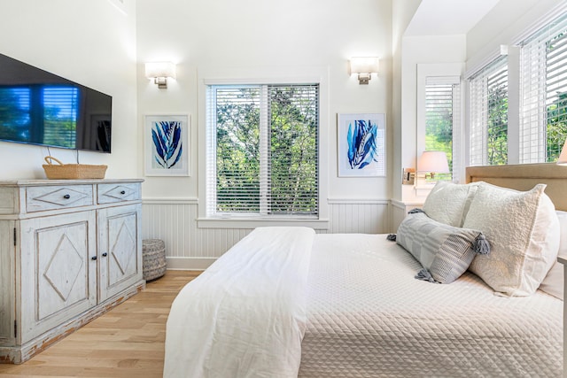 bedroom with light wood-type flooring and wainscoting