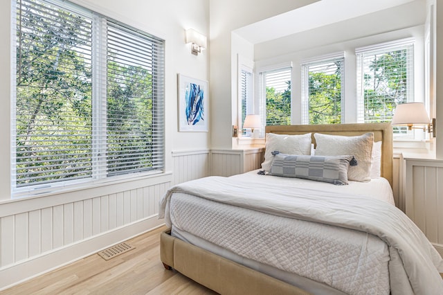 bedroom with visible vents, wainscoting, and light wood-style flooring