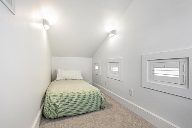 carpeted bedroom featuring lofted ceiling and baseboards