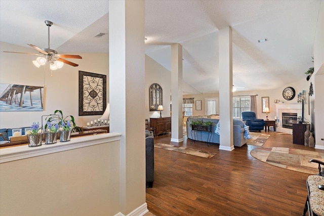 interior space featuring lofted ceiling, a textured ceiling, wood finished floors, visible vents, and baseboards