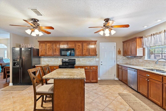 kitchen with brown cabinetry, visible vents, a sink, and black appliances