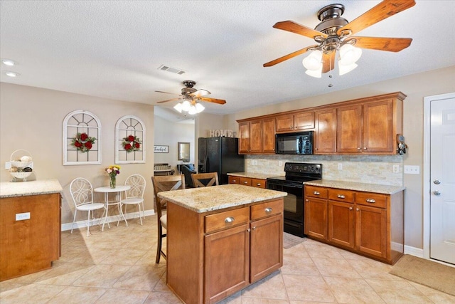 kitchen featuring visible vents, decorative backsplash, a breakfast bar area, brown cabinets, and black appliances