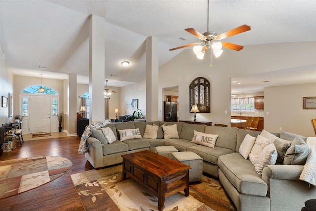 living room with light wood-type flooring, a textured ceiling, high vaulted ceiling, and a ceiling fan