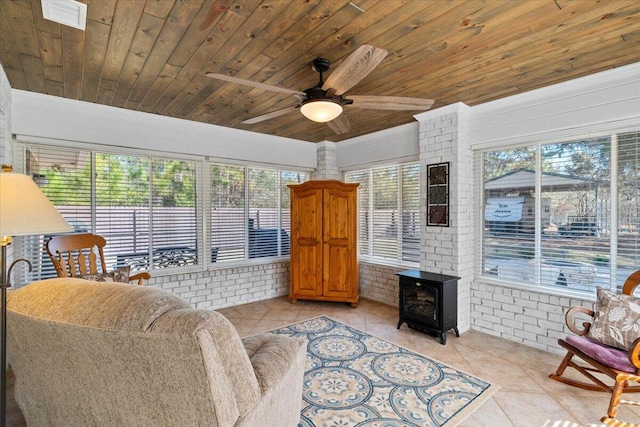 living area with brick wall, light tile patterned flooring, wooden ceiling, and a wood stove