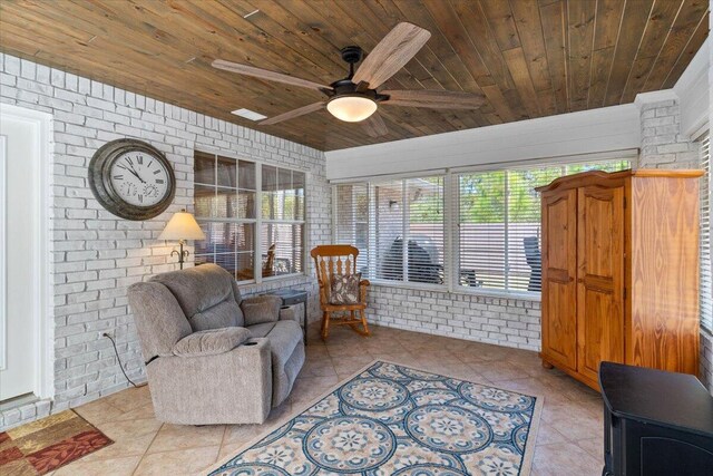 living area with ceiling fan, brick wall, wooden ceiling, and tile patterned flooring