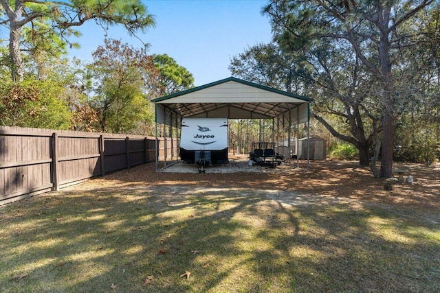 view of yard with an outdoor structure, fence, dirt driveway, a detached carport, and a storage unit