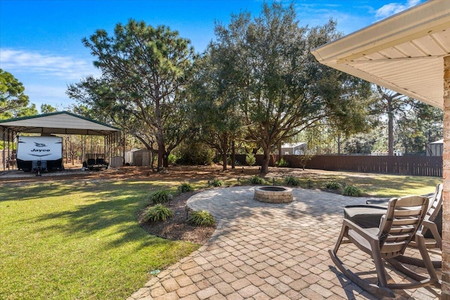 view of patio featuring a detached carport, a storage shed, an outdoor fire pit, fence, and an outdoor structure