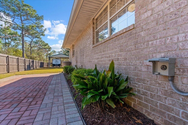 view of side of home featuring brick siding and fence