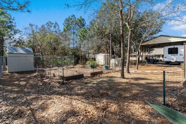 view of yard featuring a storage shed, an outdoor structure, fence, a vegetable garden, and a carport