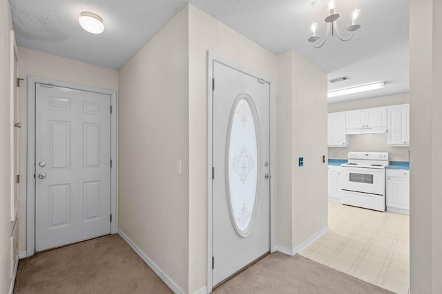 entrance foyer with a chandelier, a textured ceiling, visible vents, baseboards, and light floors