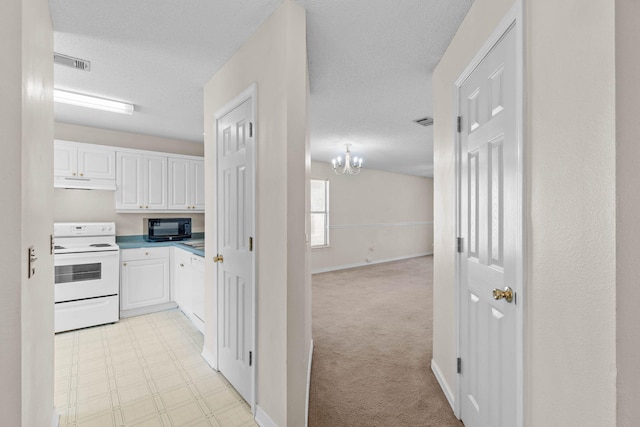 kitchen featuring black microwave, visible vents, electric stove, under cabinet range hood, and white cabinetry