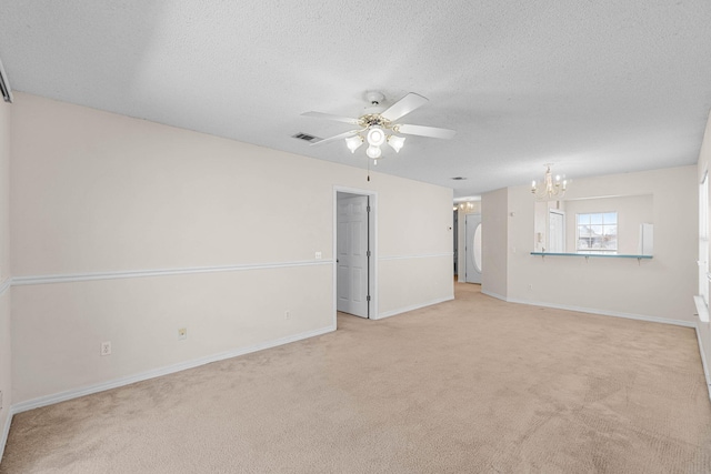 spare room featuring a textured ceiling, light colored carpet, ceiling fan with notable chandelier, visible vents, and baseboards