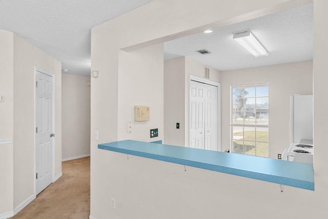 kitchen with white appliances, carpet, visible vents, and a textured ceiling