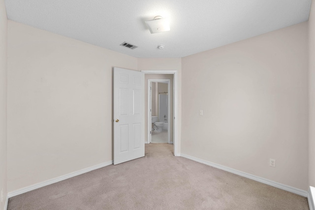 empty room featuring baseboards, visible vents, a textured ceiling, and light colored carpet