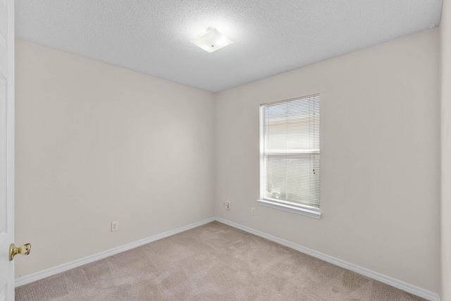 empty room featuring baseboards, a textured ceiling, and light colored carpet