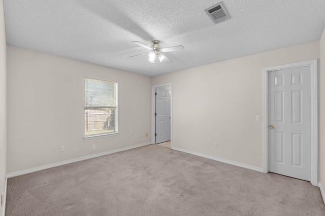 spare room featuring carpet floors, visible vents, a ceiling fan, a textured ceiling, and baseboards