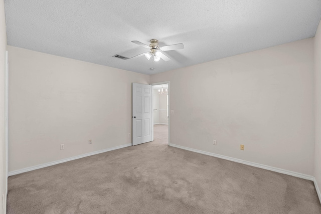 spare room featuring a textured ceiling, carpet floors, visible vents, and baseboards