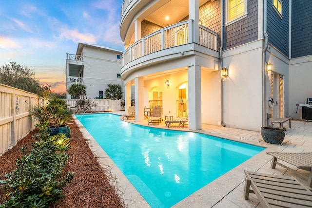 pool at dusk with a fenced backyard, a fenced in pool, and a patio