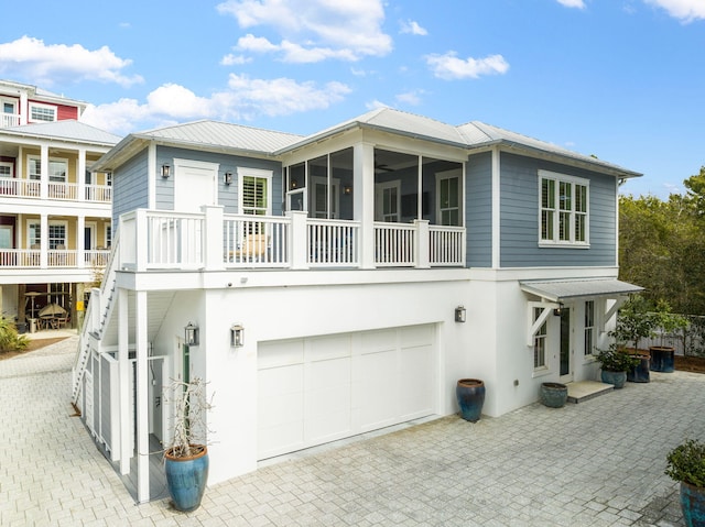 back of house featuring a sunroom, metal roof, and stucco siding