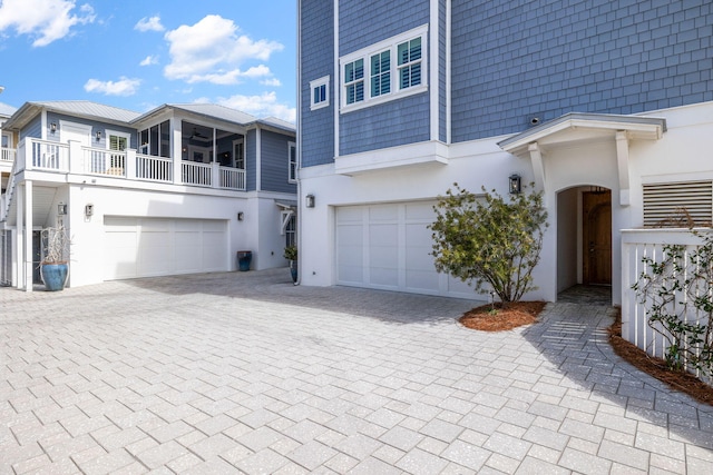 view of front of home with decorative driveway, an attached garage, and stucco siding