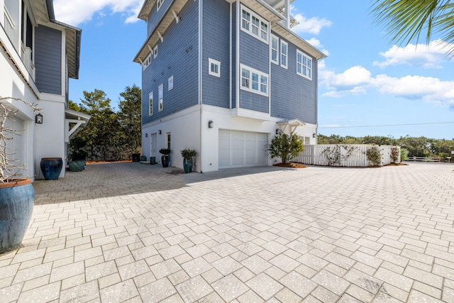 view of side of home featuring a garage, decorative driveway, and stucco siding