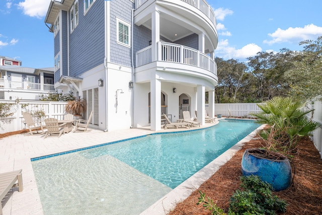 rear view of house featuring a balcony, a fenced backyard, a fenced in pool, and a patio