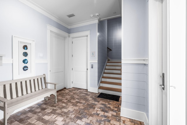 foyer with brick floor, stairs, visible vents, and wainscoting