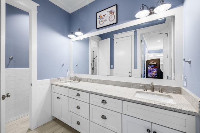 bathroom with wood finished floors, wainscoting, a sink, and double vanity